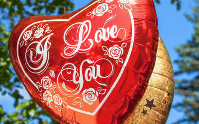 I love you heart balloon against a blue sky with trees