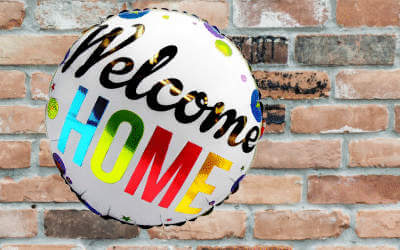 A welcome home balloon with a brick wall background